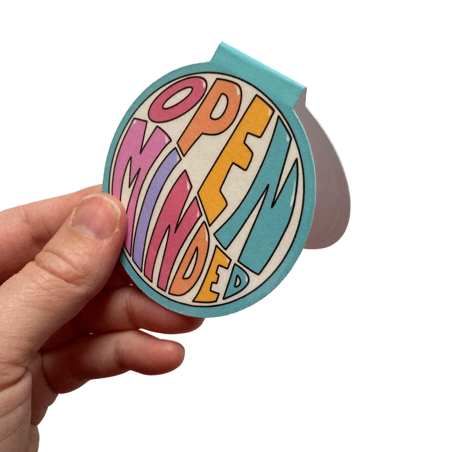Hand holding a round magnetic bookmark open over a white background. Bookmark features a teal border with the words Open Minded in colorful letters