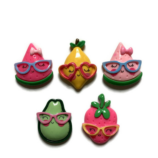 Five large fruit magnets on white background, including dark pink watermelon, yellow lemon, light pink watermelon, green avocado, and dark pink strawberry. All fruit are wearing eyeglasses.