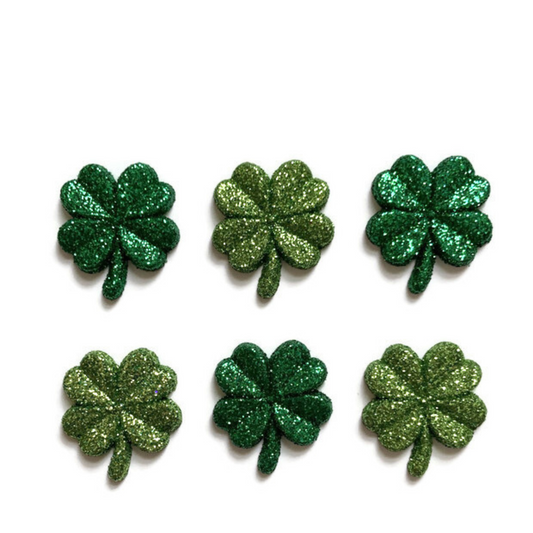 Three dark green and three light green glitter shamrock magnets on white background.